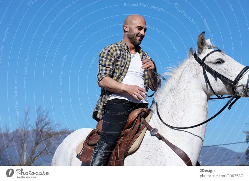 Junger Mann in lässigem Outfit reitet weißes Pferd auf sandigem Boden Reiterin pferdeähnlich horizontal gehorsam Ranch Kreatur Dressur Pferderücken Jockey