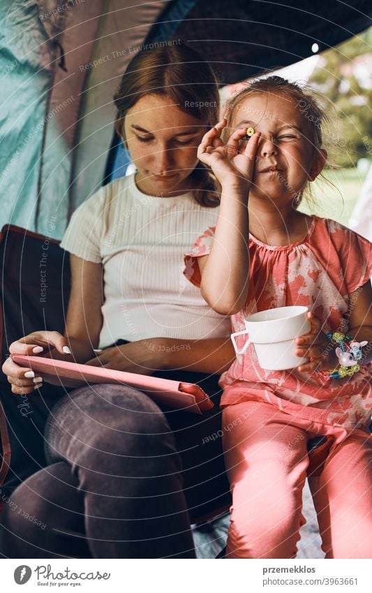 Schwestern verbringen Zeit in einem Zelt auf dem Campingplatz. Kinder mit Tablet spielen Spiele online während der Sommerferien Spielen Mädchen Geschwister