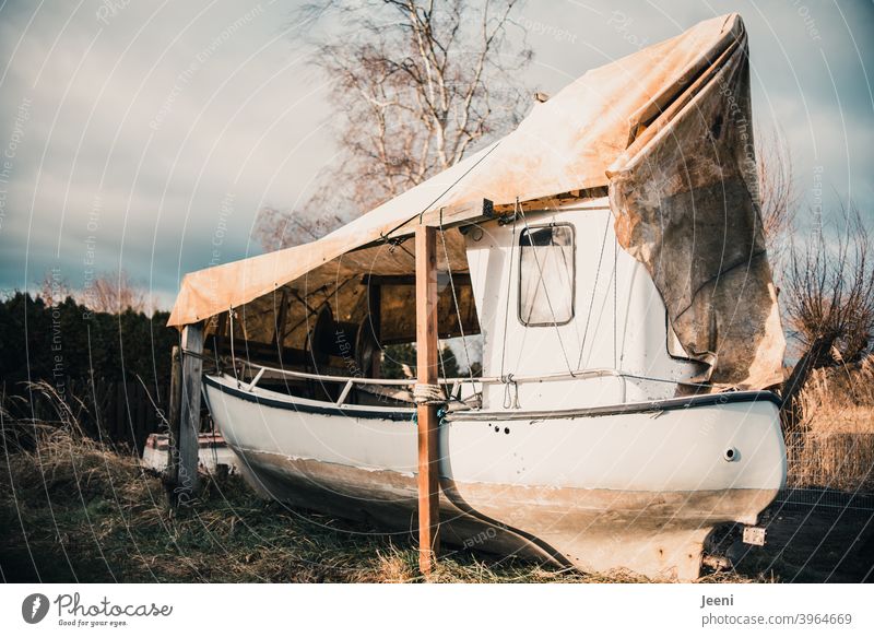 Ein für den Winter an Land festgemachtes Fischerboot in einem kleinen Fischereihafen Fischerdorf Boot abgedeckt an Land bringen trockengelegt trocken gelegt