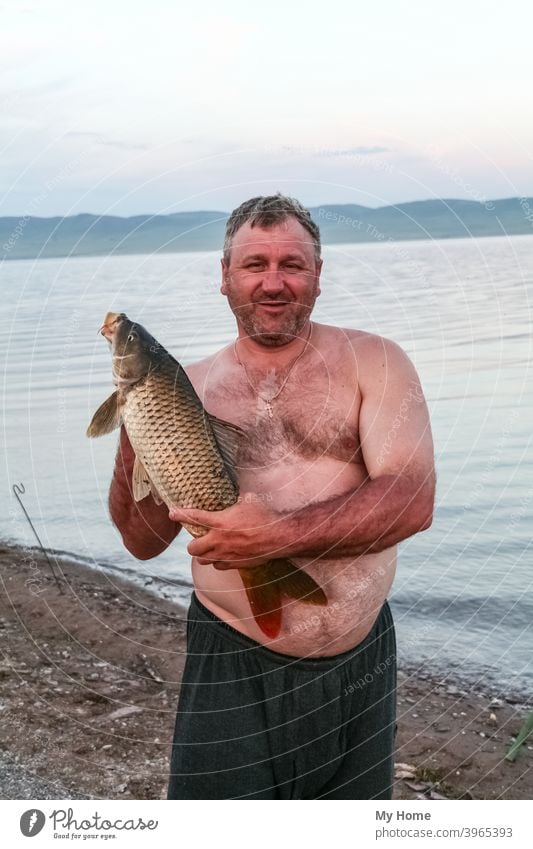 Stämmiger Mann mit Fisch. Chakassien, Russland Herbst Hintergrund Strand schön groß blau Lager Karpfen fangen Fischer Fischen gold Glück Hobby glücklich Natur