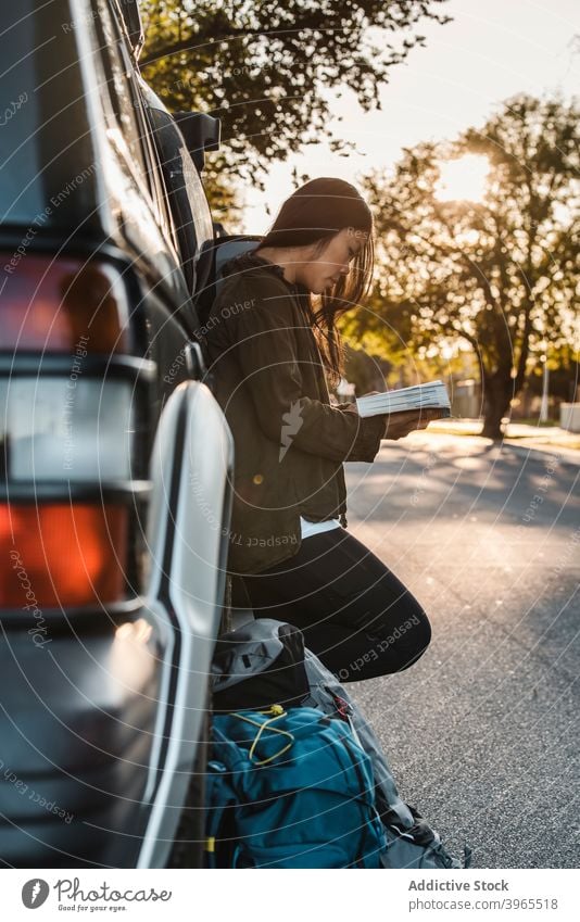 Reisende ethnische Frau liest Buch in der Nähe von Auto Reisender lesen Backpacker PKW Sonnenuntergang sich[Akk] entspannen genießen Rucksack asiatisch