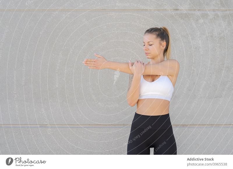 Schlanke Frau streckt die Arme beim Training Sportlerin Dehnung Aufwärmen Athlet beweglich schlank Großstadt Gesundheit Gebäude urban Leggings Sportbekleidung