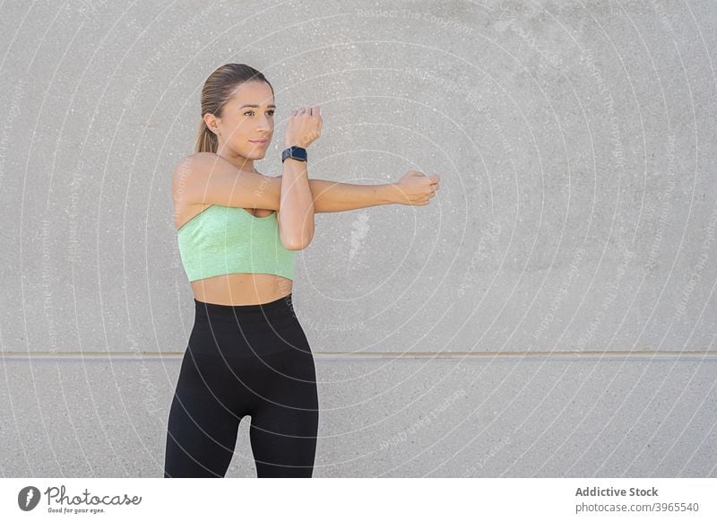 Schlanke Frau streckt die Arme beim Training Sportlerin Dehnung Aufwärmen Athlet beweglich schlank Großstadt Gesundheit Gebäude urban Leggings Sportbekleidung