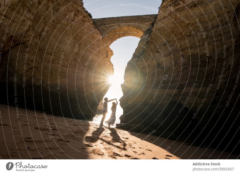 Unkenntlich Paar genießen Meerblick von sandigen Ufer in der Nähe von felsigen Klippen sich[Akk] entspannen Strand Reisender Liebe Partnerschaft sonnig