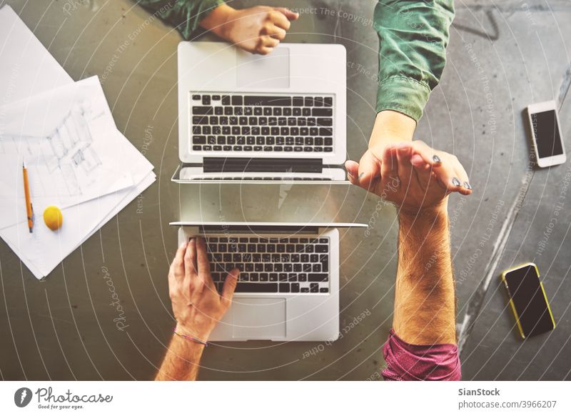 Draufsicht auf Architekten geben High-Five während der Arbeit am Computer im Büro Laptop Business Arbeitsplatz Hände Keyboard Schreibtisch Hand Tisch arbeiten