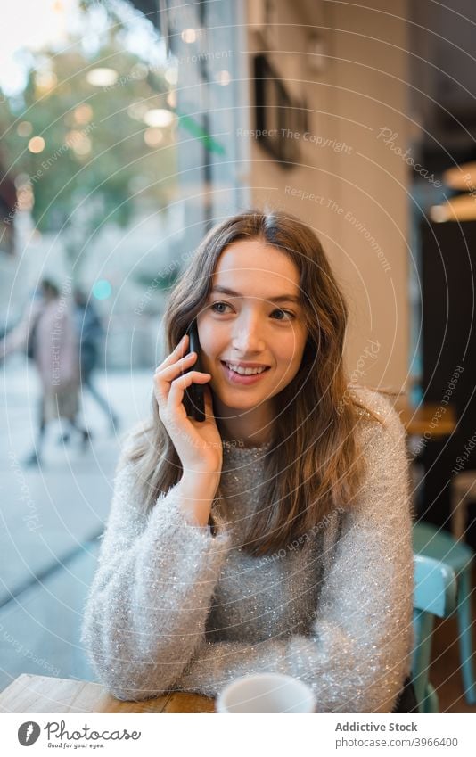 Frau spricht auf Smartphone im Café reden Lächeln diskutieren sprechen Kantine sich[Akk] entspannen Kälte Gerät Tisch charmant heiter Inhalt Anschluss modern