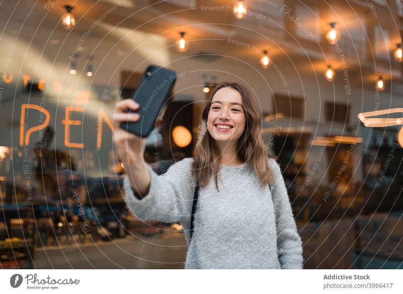 Fröhliche Frau nimmt Selfie auf Smartphone in der Stadt heiter Großstadt Wochenende Selbstportrait charmant Lächeln fotografieren Café Fenster Mobile Glück froh