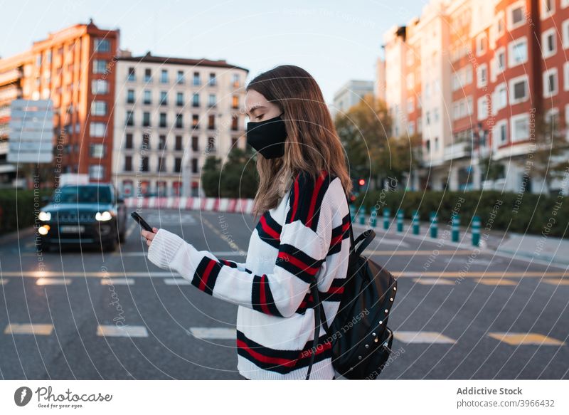 Frau beim Überqueren der Straße in der Stadt durchkreuzen Zebrastreifen Großstadt Browsen Smartphone Mundschutz Coronavirus neue Normale Pandemie jung Bund 19