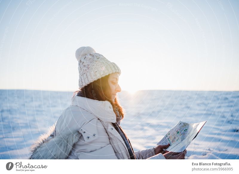 schöne junge Frau bei Sonnenuntergang in verschneiten Berg Lesen einer Karte. Reisen, Natur und Technologie-Konzept. Wintersaison Landkarte Berge u. Gebirge