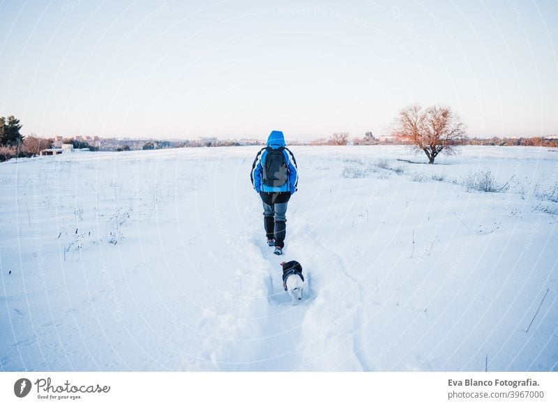 Rückenansicht von glücklichen Mann in verschneiten Berg bei Sonnenuntergang. Reisen und Sport im Freien Konzept. Wintersaison Hund jack russell Berge u. Gebirge