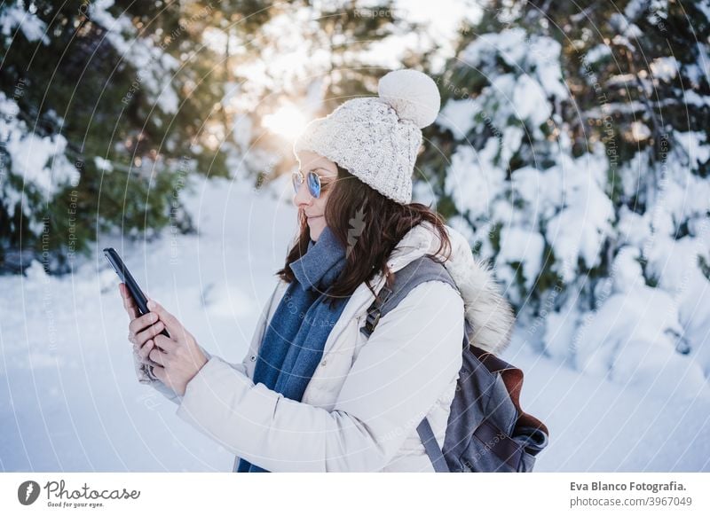 schöne junge Frau bei Sonnenuntergang in verschneiten Berg mit Handy. Natur und Technik Konzept. Wintersaison Technik & Technologie Berge u. Gebirge Schnee