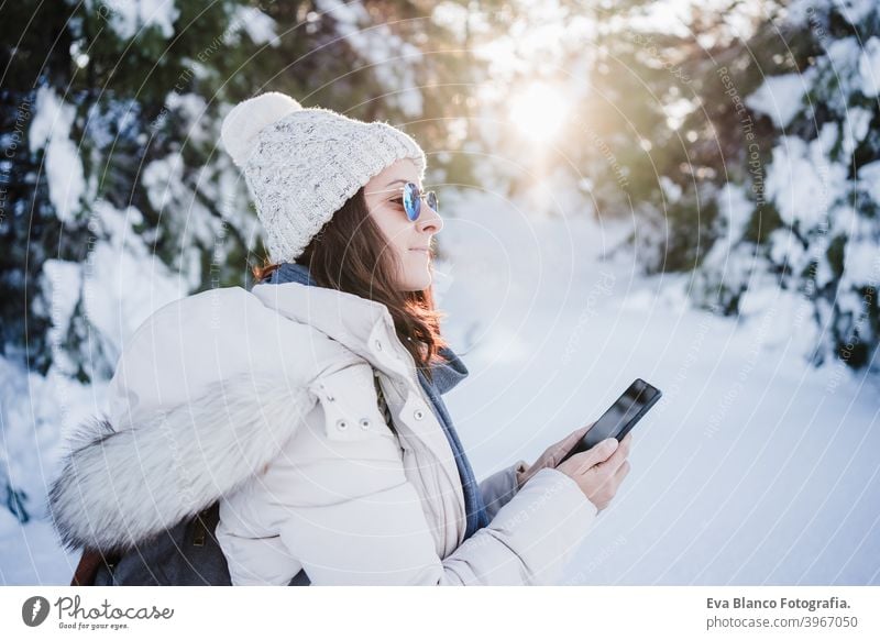 schöne junge Frau bei Sonnenuntergang in verschneiten Berg mit Handy. Natur und Technik Konzept. Wintersaison Technik & Technologie Berge u. Gebirge Schnee