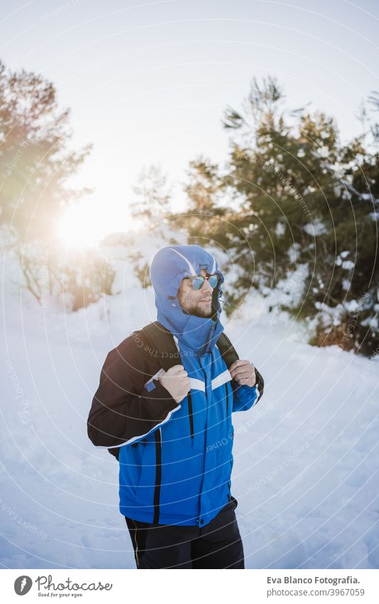 glücklich gut aussehend Mann in verschneiten Berg bei Sonnenuntergang. Reisen und Sport im Freien Konzept. Wintersaison Schnee Berge u. Gebirge wandern kalt