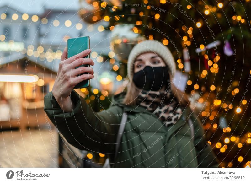 Frau in Gesichtsmaske nimmt Selfie Weihnachten Markt Mundschutz Schutz Lifestyle Fotografieren Feiertag Coronavirus Winter Tallinn Estland Großstadt Saison