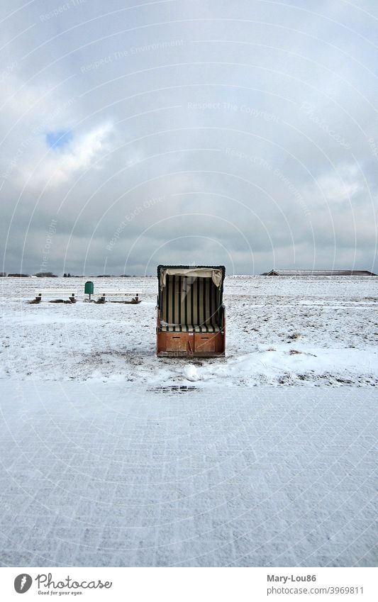 Einzelner Strandkorb im Schnee vor wolkenverhangenem Himmel Meer Insel Menschenleer Textfreiraum oben Textfreiraum unten Textfreiraum links Textfreiraum rechts