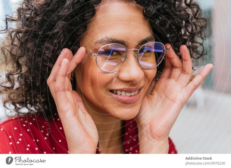 Fröhliche junge Frau mit Brille Stil trendy Mode Lächeln heiter Glück modern ethnisch ausrichten krause Haare Dame Lifestyle positiv Spektakel Inhalt Vorschein