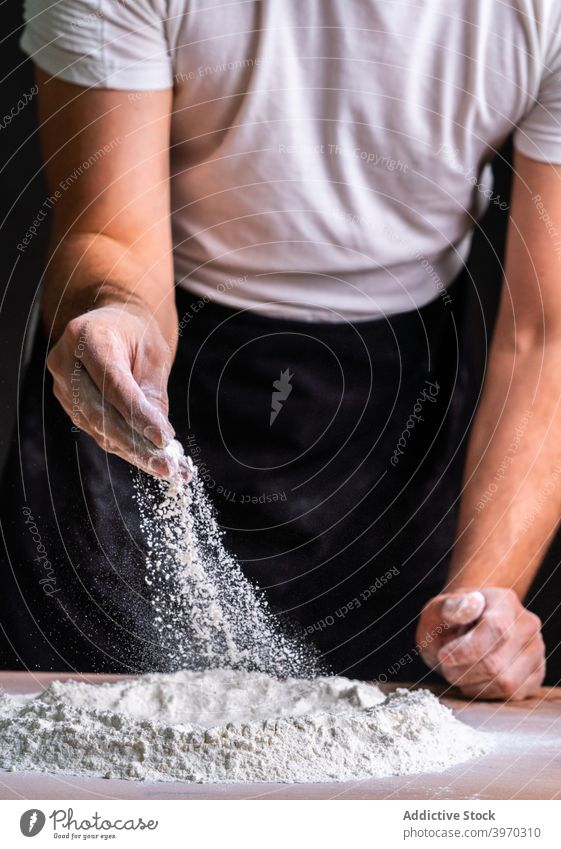 Crop Bäcker Bestäuben Hände mit Mehl machen Teig Kunstgewerbler Brot Teigwaren Staubwischen backen Weizen Koch Bestandteil Prozess natürlich Küche Haufen