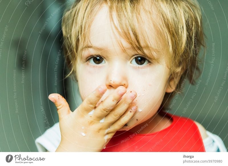 Porträt bezauberndes Kind isst Schokolade Biskuitkuchen Attribut Baby Hintergrund Lätzchen Junge braun Kuchen Bonbon Kindheit schoko niedlich lecker wüst