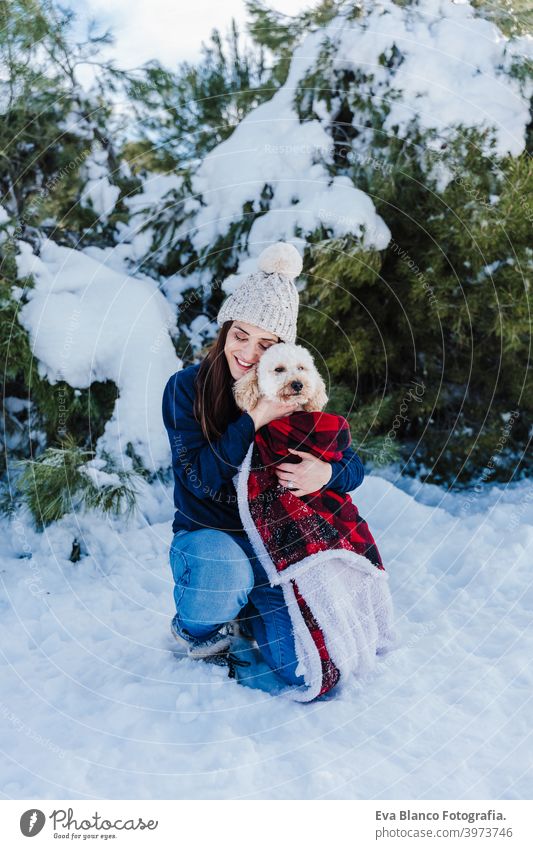 schöne Frau in verschneiten Berg Holding niedlichen Pudel Hund in den Armen in karierten Decke gewickelt. Wintersaison. Natur und Haustiere Schnee