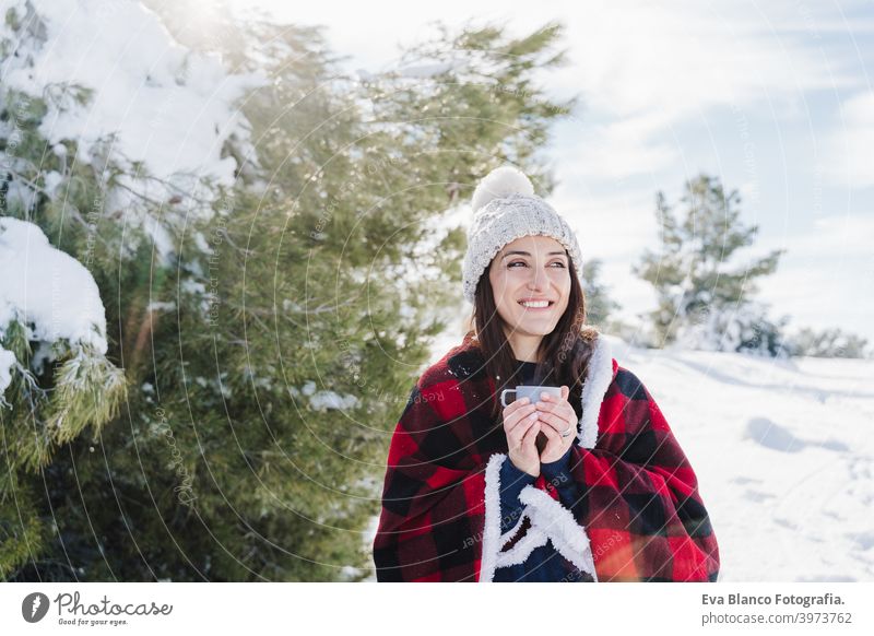 schöne Frau in karierte Decke gewickelt hält eine Tasse heißen Kaffee. Natur und Lifestyle Schnee Berge u. Gebirge Plaid heißer Tee Thermoskanne trinken sonnig