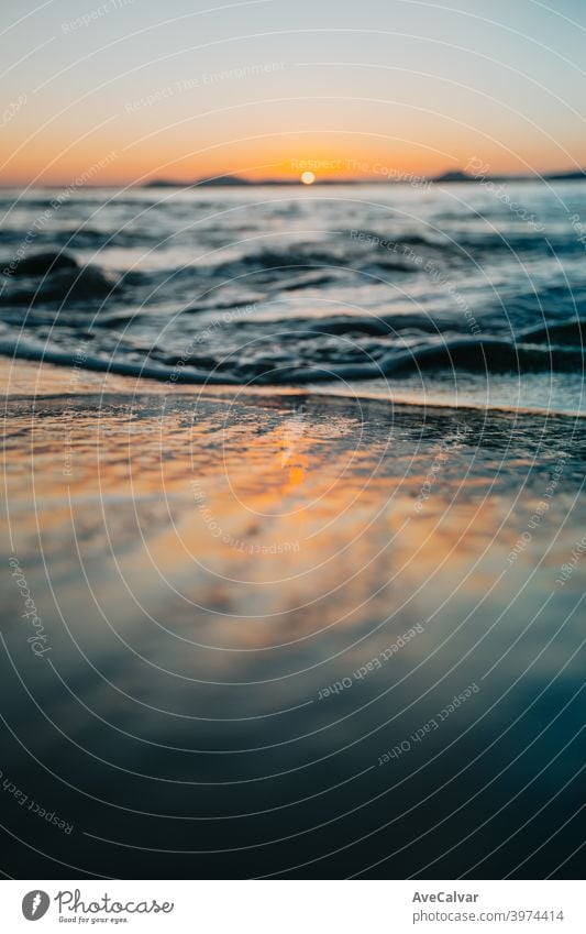 Gezeiten über den Sand des Strandes während eines Sonnenuntergangs im Frühling mit bunten Tönen Meer Reflexion & Spiegelung Sonnenaufgang winken Kopierbereich