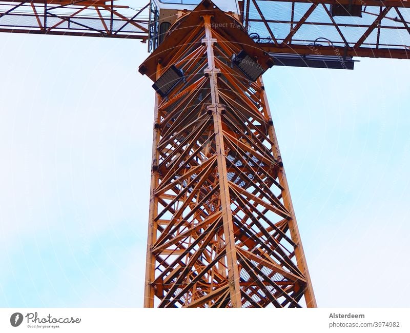 Baukran orange in dem der Aufstieg zur Kabine zu sehen ist sowie die Teil der Kabine von unten und der Ausleger Baustelle Kran Himmel blau Lastkran Tag