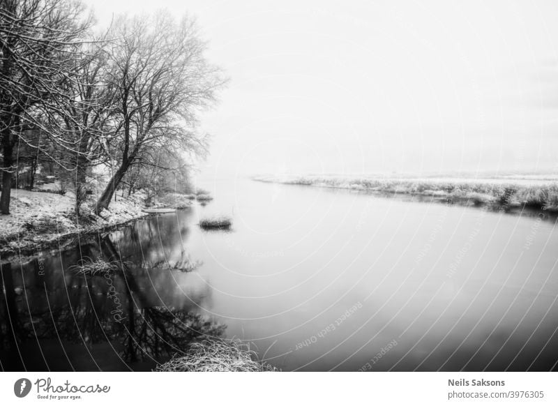 ruhiges Wasser im lettischen Winter / Fluss in der Nähe meines Hauses / der Tag, an dem sich Eis auf dem Wasser bildet / Sonnenaufgang über dem Land Herbst