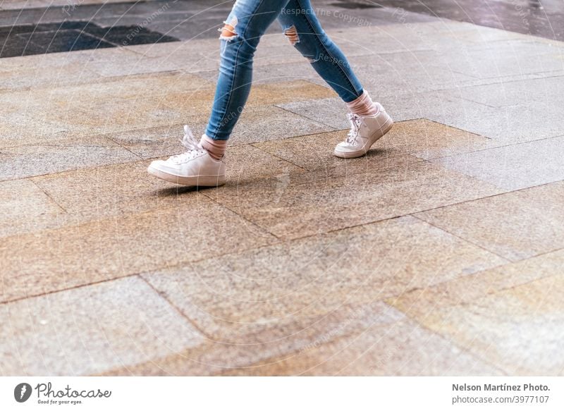 Nahaufnahme einer Frau, die auf nassem Asphalt auf der Straße läuft. Großstadt kaufen Lifestyle Kleidung Mode Leben Erholung verschwenden Business Winter Marke