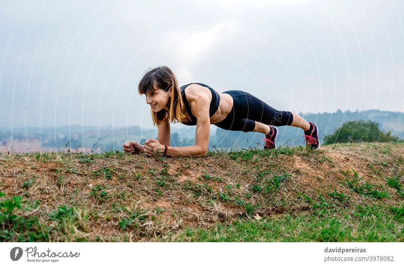 Weibliche Athletin trainiert auf dem Brett Frau Schiffsplanken Lächeln Morgen Training Bauchmuskeln genießend Ausdauer anstrengen im Freien Sportlerin Fitness