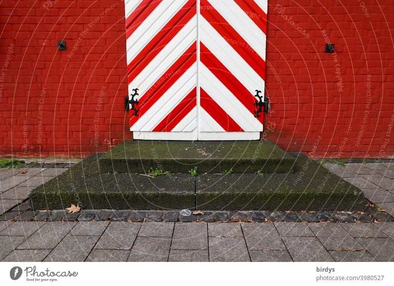 Antike Eingangstür in rot-weiß mit Stufen davor. Mittelalterliche Tür, rote Backsteinwand mittelalterlich gestreift diagonal stufen rote Wand Fassade Design