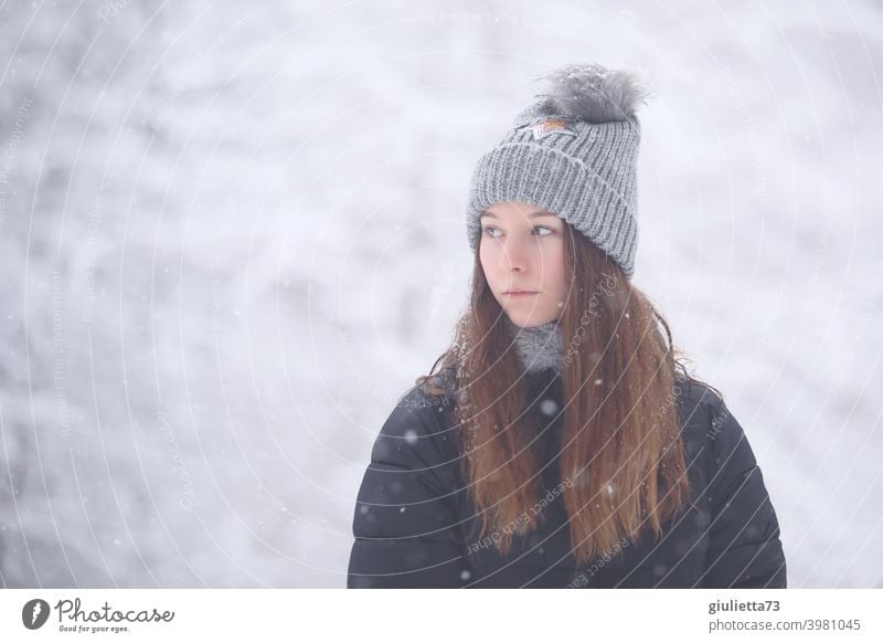 Teenager Mädchen mit melancholischem Blick draussen im verschneitem Winterwald Porträt Jugendliche Farbfoto Außenaufnahme Mütze Winterjacke Winterstimmung