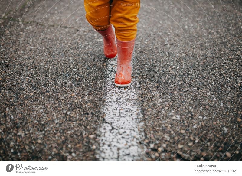 Close up Kind rote Gummistiefel zu Fuß die Linie laufen nass Kindheit Wasser Mensch Freude Außenaufnahme Regen Spielen Farbfoto Herbst Stiefel Tag Wetter Pfütze