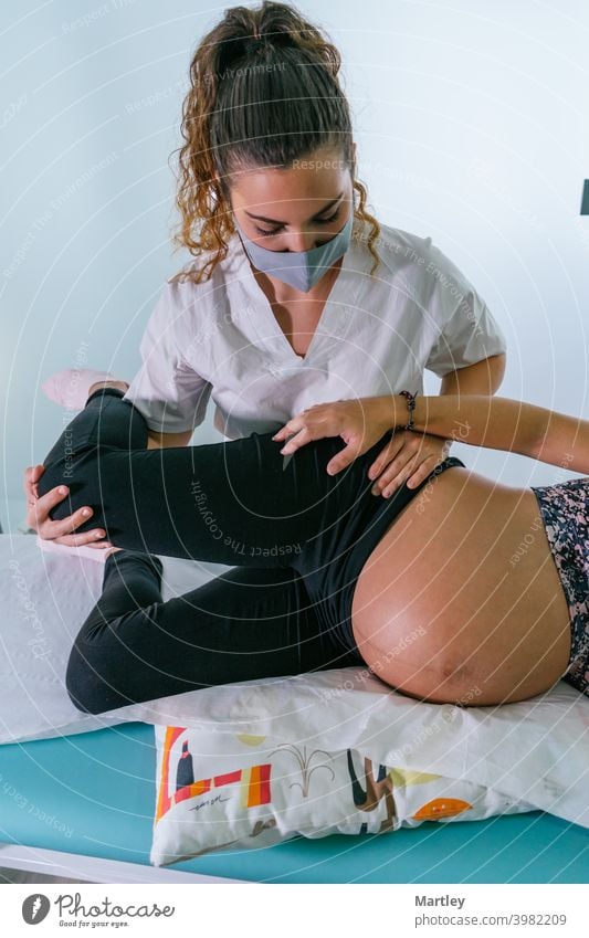 Weibliche Therapeutin dehnt das Bein einer Schwangeren während einer Physiotherapie-Sitzung in einer modernen Klinik. Schwangerschaft schwanger pränatal