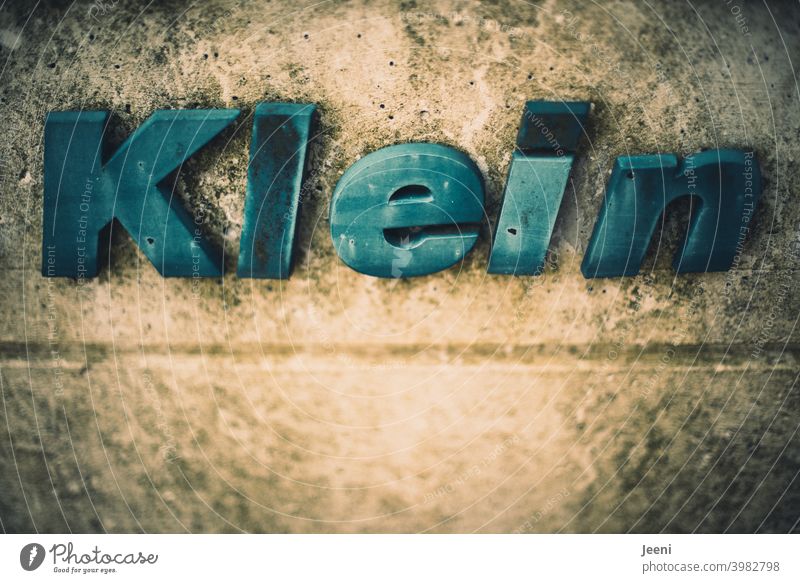 Manchmal fühlt man sich ganz klein | an einer dreckigen Wand steht das Wort "Klein" geschrieben | Textfreiraum unterhalb Groß blau alt schäbig Typographie