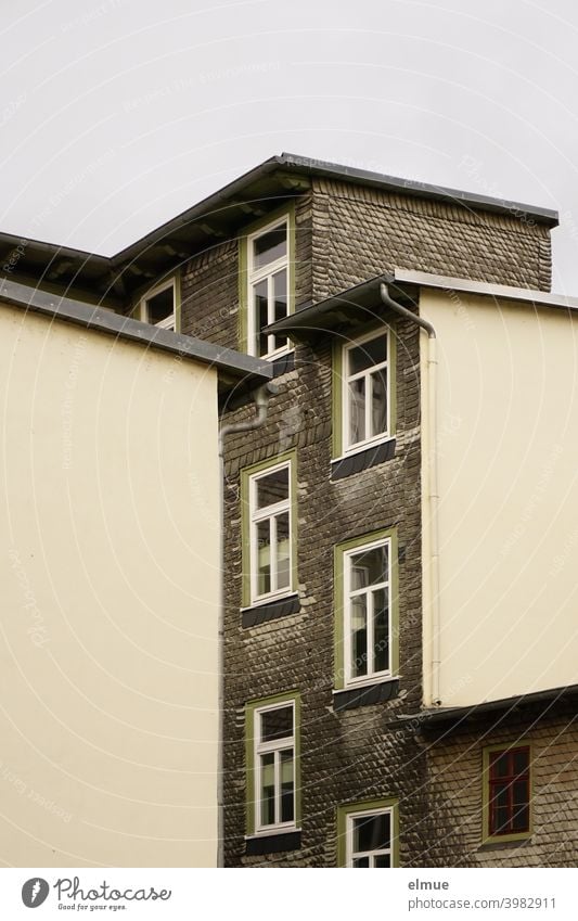 Einblick in einen Innenhof auf ein renoviertes Schieferhaus mit zahlreichen versetzten Fenstern Wohnhaus verkleidet wohnen Fassade Hinterhof Schiefergestein