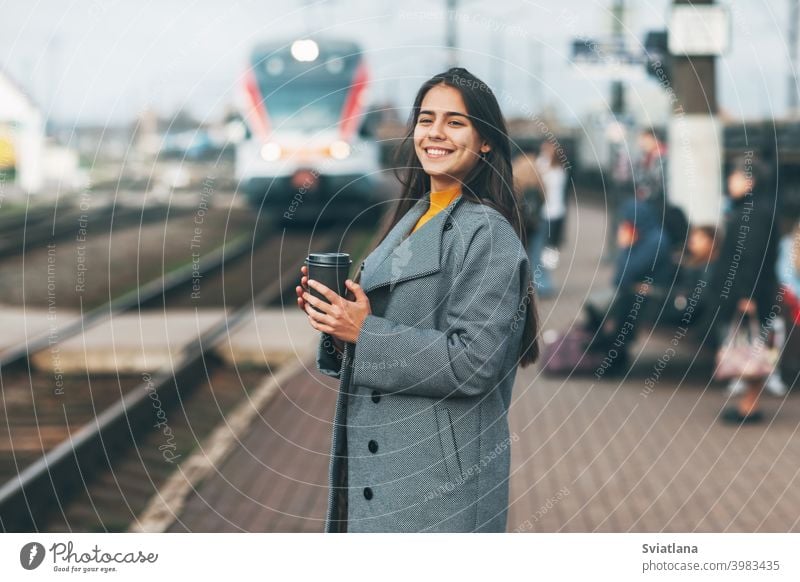 Fröhliches Mädchen steigt am Bahnhof mit Kaffee in der Hand in den Zug ein. Verkehr jung Frau schön Eisenbahn Passagier U-Bahn Lächeln Öffentlich Station Warten