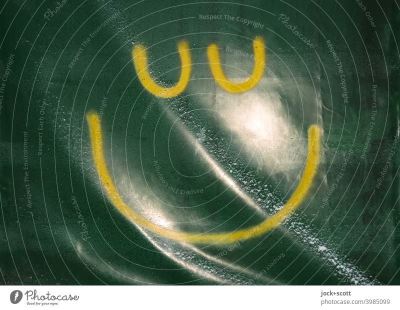 gelber Smiley auf wellige grünliche Plastikplane gesprüht Plane Reflektion Schneeflocke Strukturen & Formen einfach Kunststoff Straßenkunst Detailaufnahme