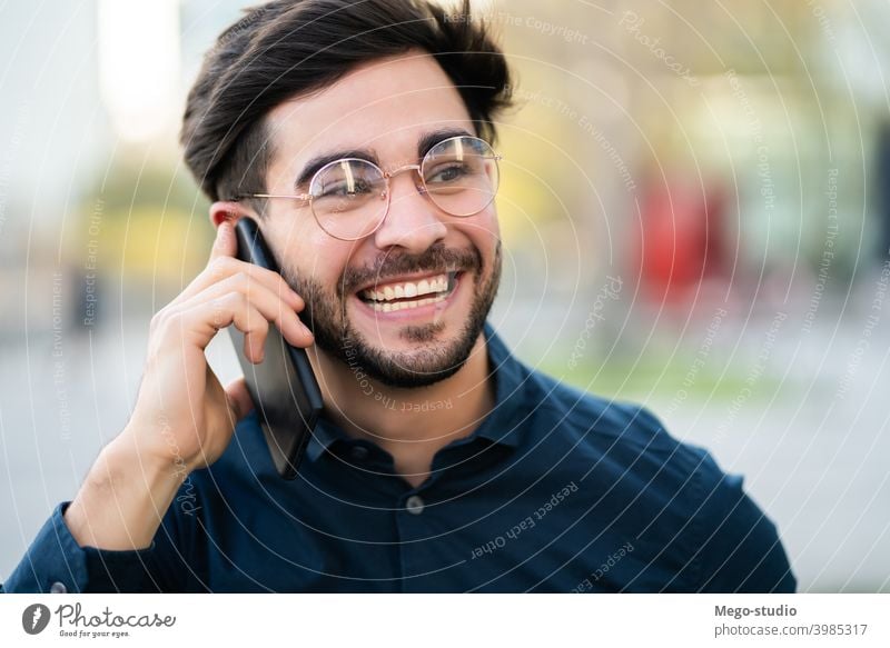 Junger Mann beim Telefonieren im Freien. jung Mobile urban Lächeln Anschluss Apparatur Porträt positiv Drahtlos Beteiligung laufen Blick Tippen sprechend reden