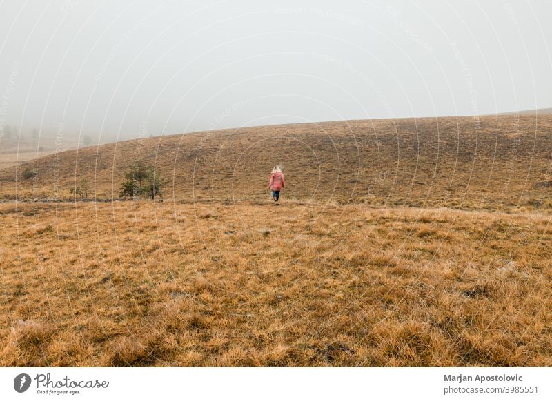 Junge Frau erkundet die Natur an einem nebligen Wintermorgen Abenteuer Herbst Cloud kalt Landschaft Fundstück Erkundung erkunden Entdecker Feld Nebel Freiheit