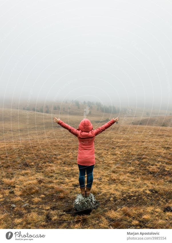 Junge Frau erkundet die Natur an einem nebligen Wintermorgen Abenteuer Herbst Cloud kalt Landschaft Fundstück Erkundung erkunden Entdecker Feld Nebel Freiheit