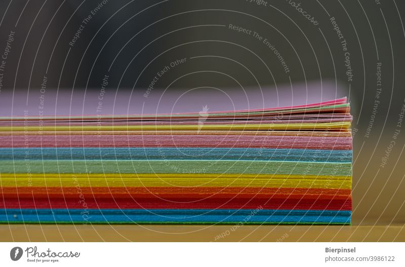 Ein Stapel mehrfarbiges Kopierpapier auf einem Schreibtisch zu Hause Papier Homeoffice Material bunt blau rot rosa gelb grün gestapelt Heimarbeit Arbeitszimmer