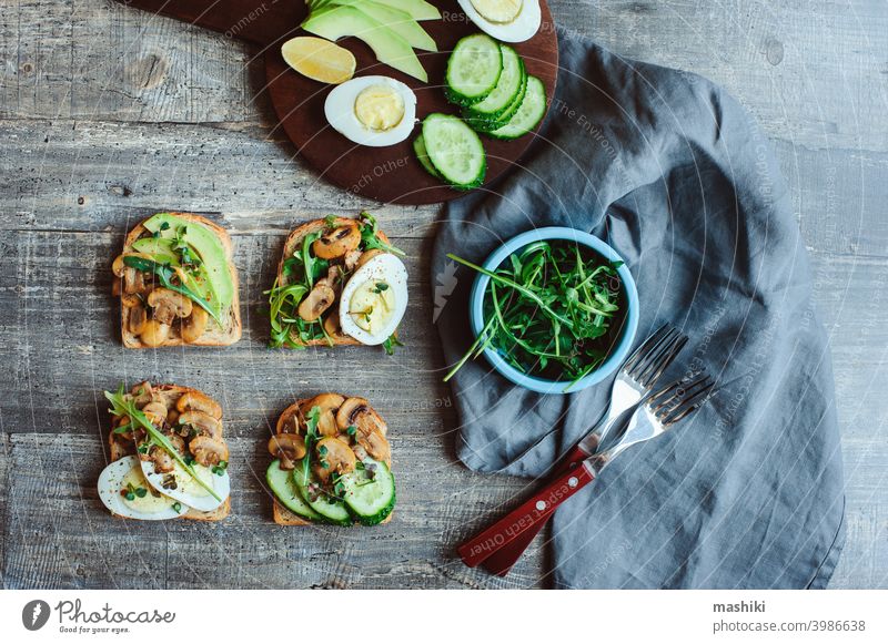 verschiedene Morgen vegetarischen Toast Set mit Pilzen, Avocado, Rucola, Gurke, Mikro grün und Eier. Gesundes Essen auf rustikalem Holzhintergrund Zuprosten