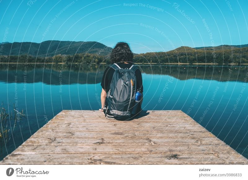 Mädchen sitzt auf dem Rand des Banyoles See mit der Landschaft im Wasser reflektiert Harmonie Meditation entspannend horizontal Profil Ruhe Person nachdenken