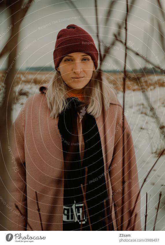 Portrait einer modisch gekleideten Frau in Winterlandschaft winterwonderland frau junge frau mantel spaziergang schnee sonne licht natur schal mütze lange haare