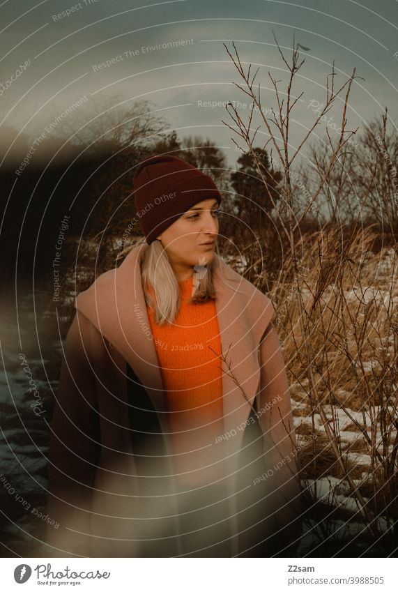 Portrait einer modisch gekleideten Frau in Winterlandschaft winterwonderland frau junge frau mantel spaziergang schnee sonne licht natur schal mütze lange haare