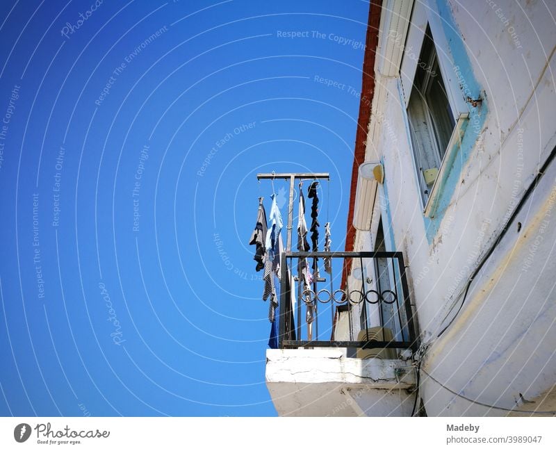 Altes weißes Haus mit Balkon und Wäscheleine vor strahlend blauem Himmel im Sommer bei Sonnenschein in Alacati bei Izmir am Ägäischen Meer in der Türkei