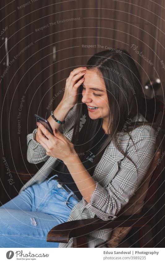 Junge Frau prüft und tippt auf ihrem Mobiltelefon. schwarz Heißgetränk Smartphone Lifestyle Glück schön Beteiligung Person Blick Texten Tasse Mädchen Cafés