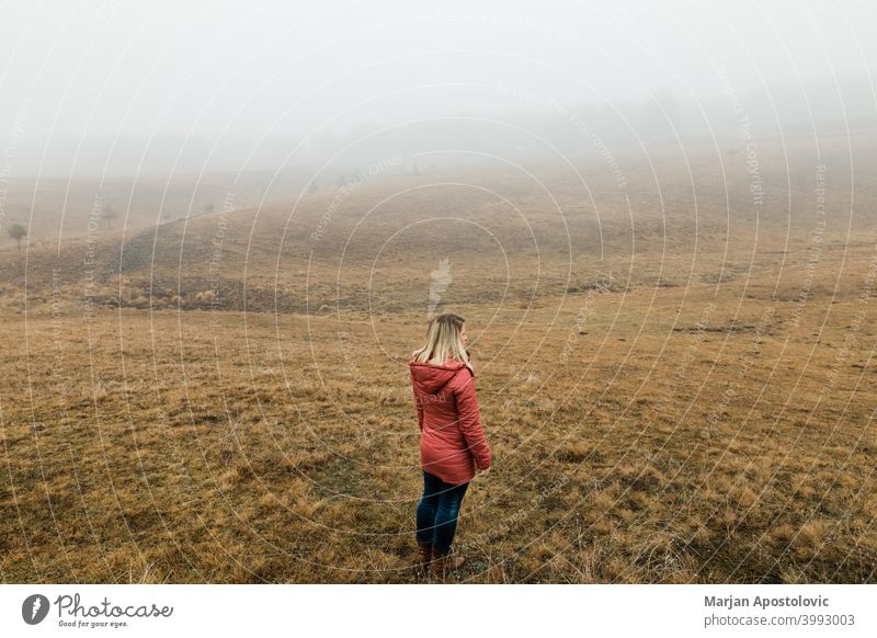 Junge Frau erkundet die Natur an einem nebligen Wintermorgen Abenteuer Herbst Cloud kalt Landschaft Fundstück Erkundung erkunden Entdecker Feld Nebel Freiheit