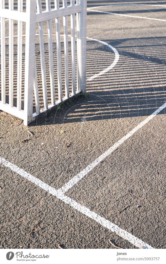 Holzzaun auf Sportplatz weiß sport sportplatz grau hell sonne schatten Sonnenuntergang klar symetrisch linien park draußen hochformat farbfoto schwarzweiß