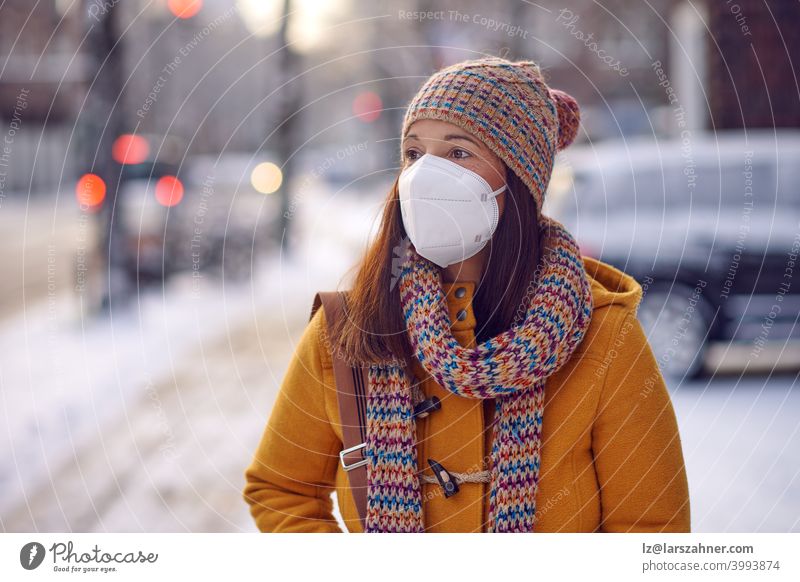 Brünette Frau mittleren Alters in Winterkleidung mit Gesichtsmaske im Freien aufgrund des Corona-Virus auf dem Weg zur Arbeit brünett Mundschutz ffp2 Schutz